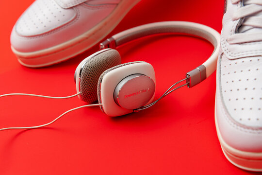 Bowers & Wilkins P3 headphones lie between white sneakers on a vivid red background.