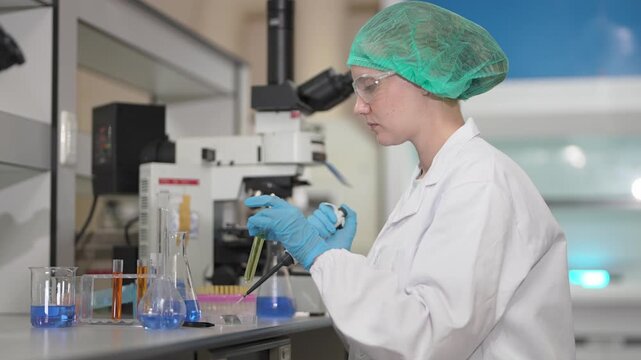 Scientist in a laboratory examining a petri dish sample under a professional light microscope