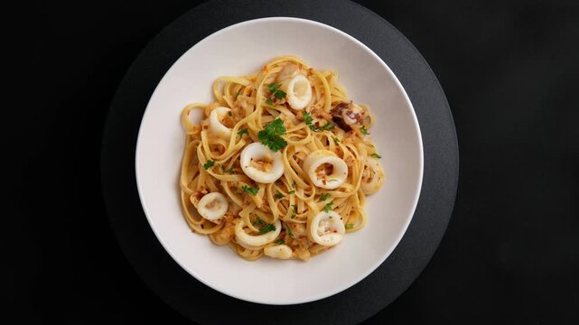 Stir fried linguine pasta with squid and chilli ,garlic with olive oil in white plate.Octopus Spaghetti Aglio e Olio.Top view.
