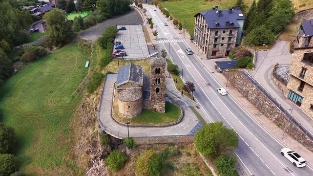Overhead view of Sant Joan de Caselles, an 11th century Romanesque church perched on a rocky outcrop in Canillo, Andorra, surrounded by alpine village and road