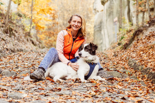 happy white dog with owner in autumn forest