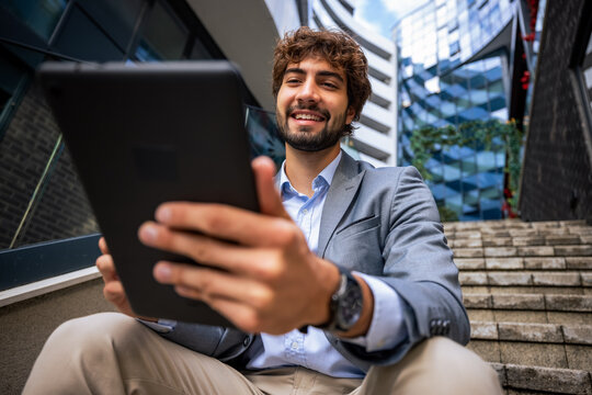 Close up portrait of smiling businessman using digital tablet outdoors