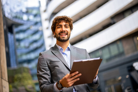  Smiling young professional man holding a clipboard