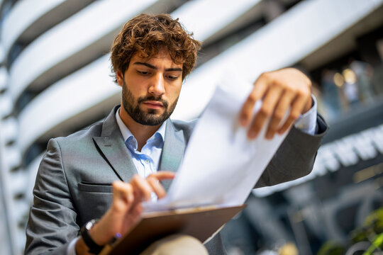 Young professional man reviewing documents on a clipboard in a modern urban office environment