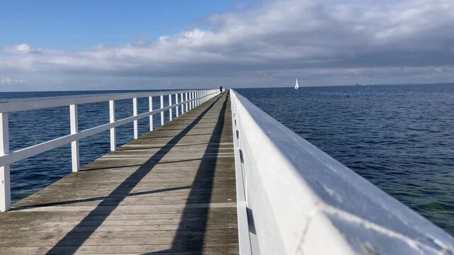 Woman walking on a pier along Ribersborg beach in Malmo during autumn