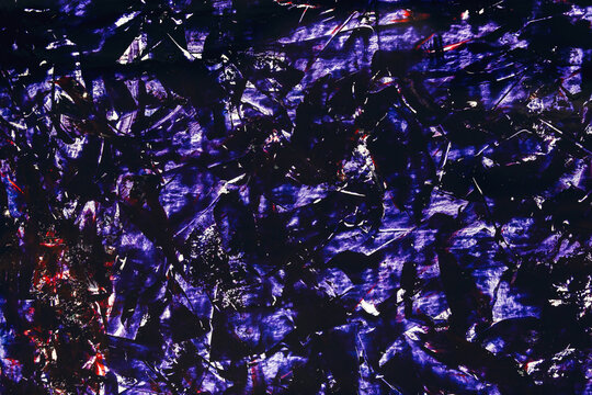 Deep purple tones swirl across a fractured, glossy surface. Light catches jagged edges, creating shimmering highlights. Dark crevices echo with shadows, suggesting depth and mystery