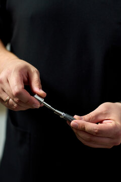 Closeup of hands threading metal hose connector fittings together, assembling garden plumbing hardware under neutral indoor lighting with sharp focus on textured threads
