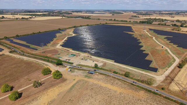 Aerial view of expansive photovoltaic solar farm array with an access road cutting through the middle near Eaton Socon, UK