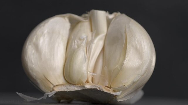 Half of a garlic bulb with plain black ground rotating showing 360 degrees of view.