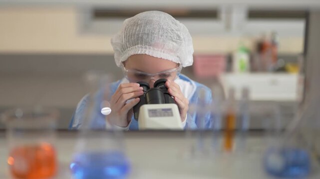 Scientist in protective gear using a microscope for research in a modern clinical laboratory setting