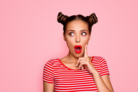 OMG! Close up face of shocked astonished girl with modern hairdo having wide open mouth and brown eyes looking at camera and to touch her cheek by finger isolated on red background with copyspace