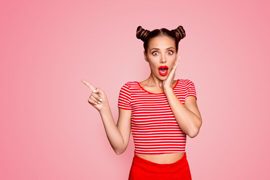 Look there! What a news! Attractive brunette girl with modern hairdo touch the cheek, having wide open mouth and brown eyes show finger on red background