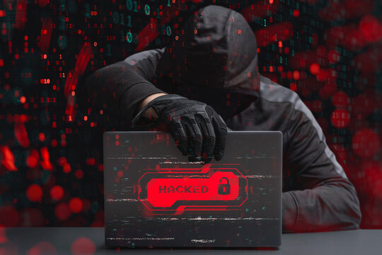 Hooded hacker with laptop showing hacked warning and unlocked padlock icon. Cybersecurity breach, data theft or ransomware attack concept with binary code background.