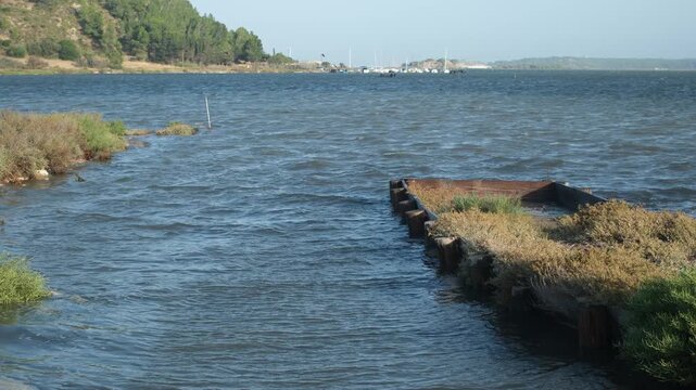 View of Bages-Sigean lagoon (&Eacute;tang de Bages-Sigean) from Peyriac-de-Mer, Occitanie region, France. Wooden groynes on the lagoon coast. Yachts in the distance.
