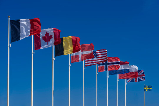 Saint-Aubin-Sur-Mer, France - 08 08 2026: Alignment of national flags of the Allies of the Second World War with a blue sky background