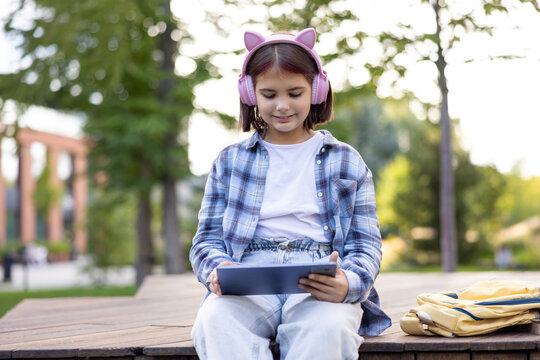 Girl learning outdoors using tablet and headphones