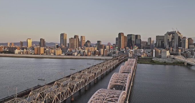 Osaka Japan Aerial v1 low flyover bridge spanning across Yodo river capturing downtown sunset cityscape of Nakatsu, Ofukacho and Oyodonaka in Kita Ward - Shot with 5k Camera - Oct 12th 2023