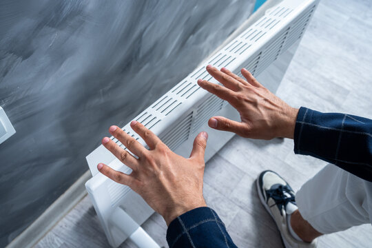 A person is warming their hands by a heater.