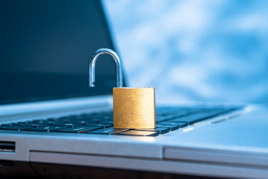 An unlocked lock is lying on the laptop keyboard.