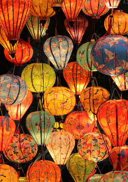 Full frame abstract texture background of illuminated colorful traditional silk lanterns hanging at night in Hoi An, Vietnam.