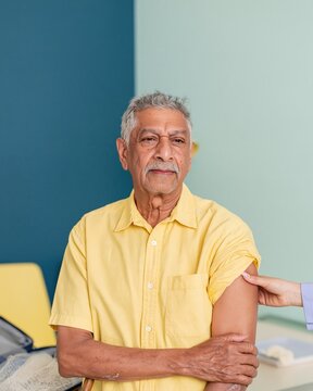South Asian man receiving a japanese encephalitis vaccine in a clinic, with a calm expression and soft daylight for travel health and insurance