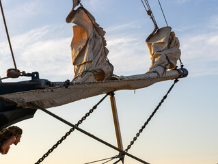 Dramatic Low-Angle View of Tall Ship Bowsprit and Furled Sails Against Blue Sky at Golden Hour © Bjorn B