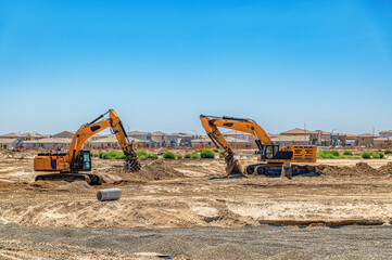 Heavy excavators operate at large construction site, preparing land for new residential development. © Todayphoto