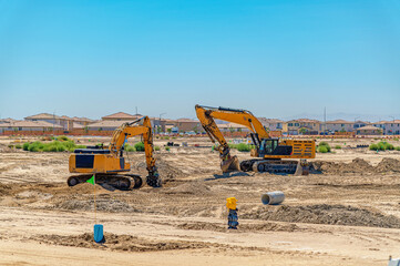 Heavy excavators operate at large construction site, preparing land for new residential development. © Todayphoto