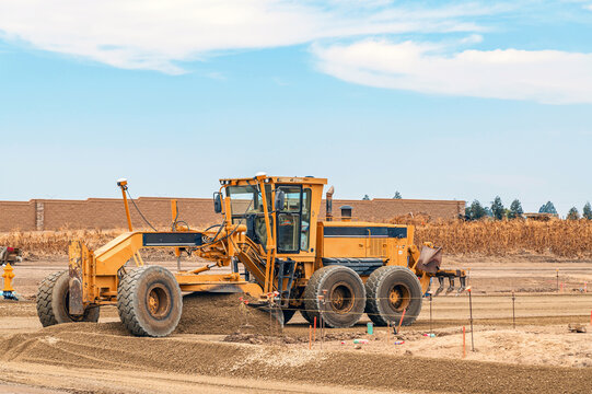 Powerful motor grader levels gravel for new road at construction site. Site preparation.
