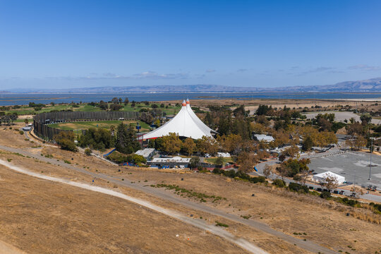 Aerial view of the tented Googleplex Shoreline Amphitheatre venue, surrounding golf driving range, and wetlands along San Francisco Bay in Mountain View, California.