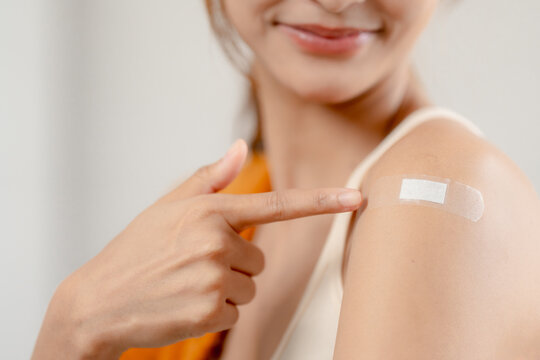 Vaccination concept, woman points to adhesive bandage on upper arm after injection. showing immunization and healthcare, vaccine, injection, prevention, immunity