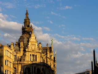 Obraz premium September 23, 2026 - Ornate Baroque Historic Building Facade Glowing in Golden Sunset Light Against Blue Sky with Clouds