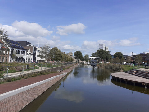 a beautiful view of port city terneuzen in zeeland with large buildings and houses along the historic canal with water and a blue sky