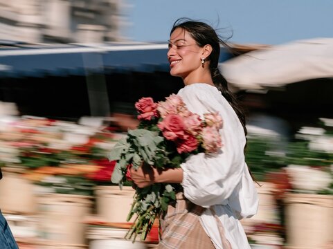 Pink roses bouquet held by a smiling Indian woman walking through a sunlit flower market, glowing and natural, for floral and lifestyle themes