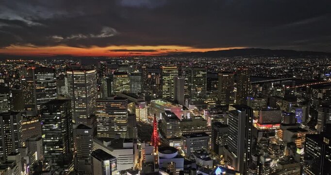 Osaka Japan Aerial v88 flyover capturing the vibrant downtown cityscape transitioning from sunset to dusk, with buildings illuminated as night falls - Shot with 5k Camera - Oct 9th 2023