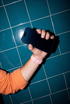 Hand Gripping Phone on Teal Wall