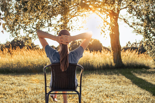 Relaxed woman enjoying peaceful golden sunset outdoors in nature, mindfulness and stress relief concept
