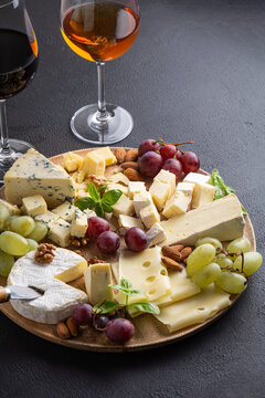 Gourmet cheese board with red and white grapes, almonds and wine glasses