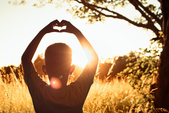 Boy Making Heart Shape With Hands at Sunset, Love, Happiness, Hope, Gratitude, Childhood and Positive Life Concept
