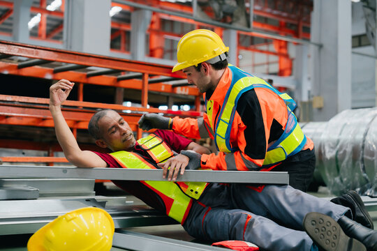 Industrious engineer helping injured worker after factory industry metal sheet accident showing worried feeling with urgent professional rescue