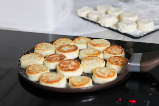 Syrnyky frying on an induction cooktop during homemade breakfast preparation