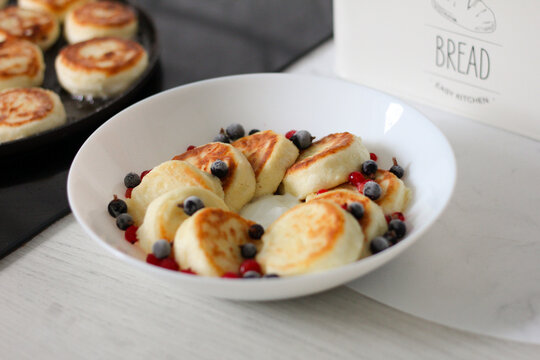 Homemade syrnyky with berries and sour cream for a traditional Ukrainian breakfast