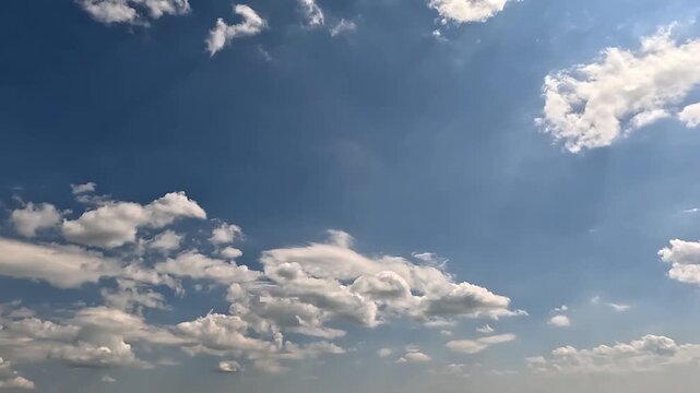Exciting endless clouds in the blue skies. 4K video (Ultra High Definition) of cloudscape and bright sun. Sky and clouds Timelapse. Sun shines through the clouds on the blue sky background.