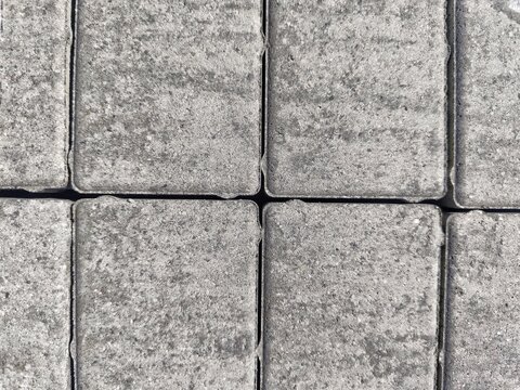 Full frame overhead background of grey rectangular interlocking concrete pavers
