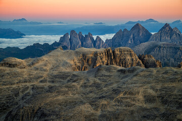 Panoramic view of rocky alpine peaks rising above a sea of clouds in the Italian Dolomites during sunrise. Ideal for outdoor adventure and travel themes. © marcodenaro