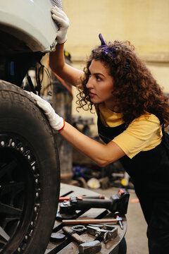 Female mechanic inspecting car wheel in auto repair shop