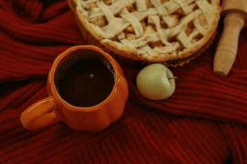 Obraz premium Homemade apple pie with a lattice top next to a cup of hot coffee and an open book, autumn leaf decor, cozy autumn reading setting, film grain effect, high-quality photo