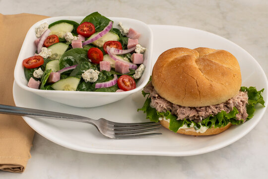 tun a salad on a bulkie roll with a spinach salad
