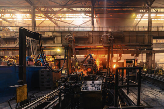 Ductile iron pipe casting machinery operating inside hot foundry, glowing metal production line for heavy industrial manufacturing and water infrastructure.