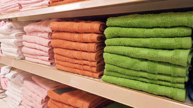 Folded colorful beach towels on store shelving for retail display background and merchandising banner use